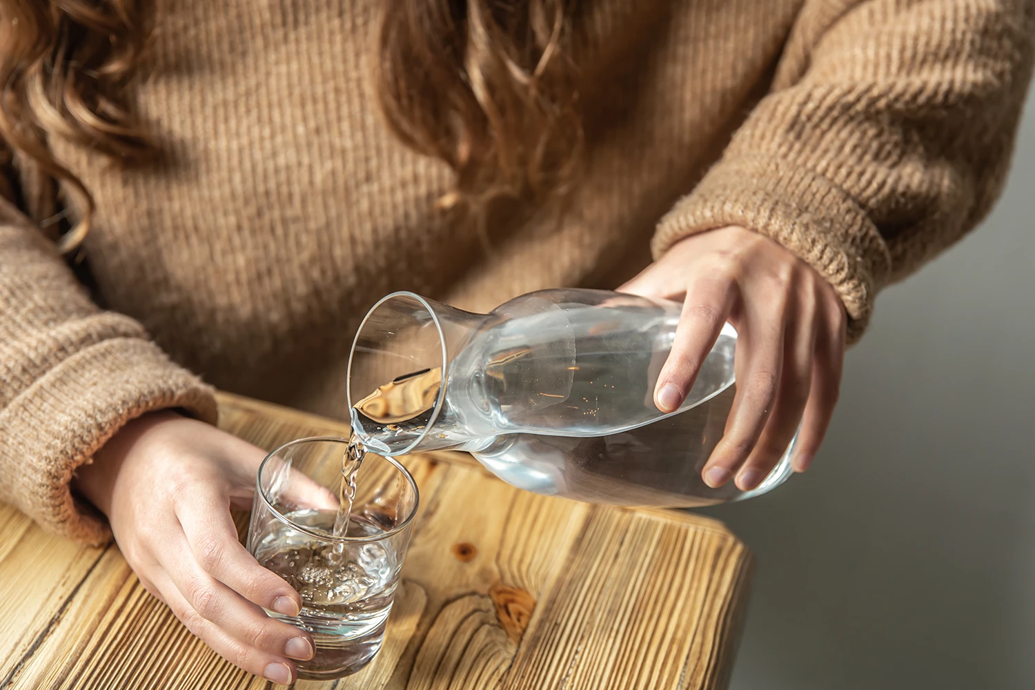 Wasser wird aus einer Karaffe in ein Glas eingefüllt