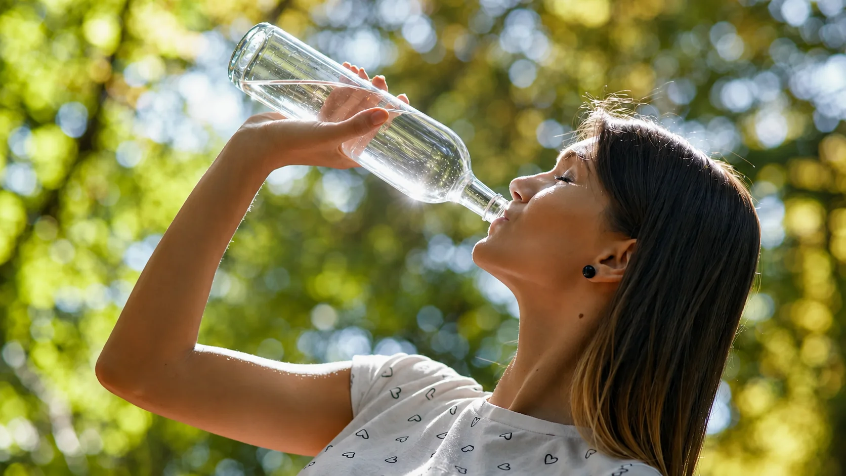 Frau Trinkt aus Glas Flasche Wasser in Großen schlücken bei Hitze